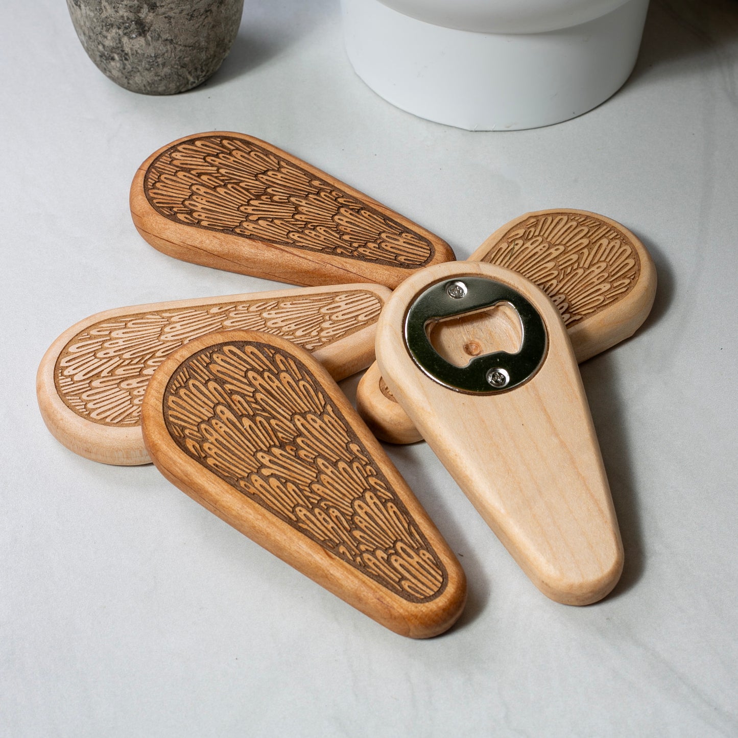 Wooden bottle opener with engraved design on a light surface