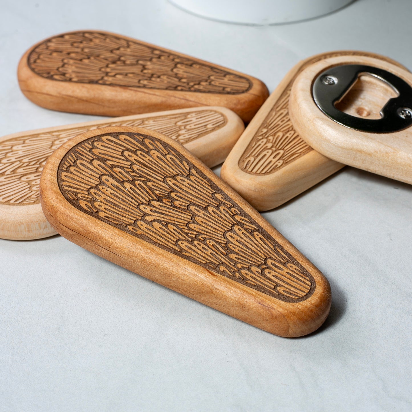 Wooden bottle openers with engraved designs on a light background