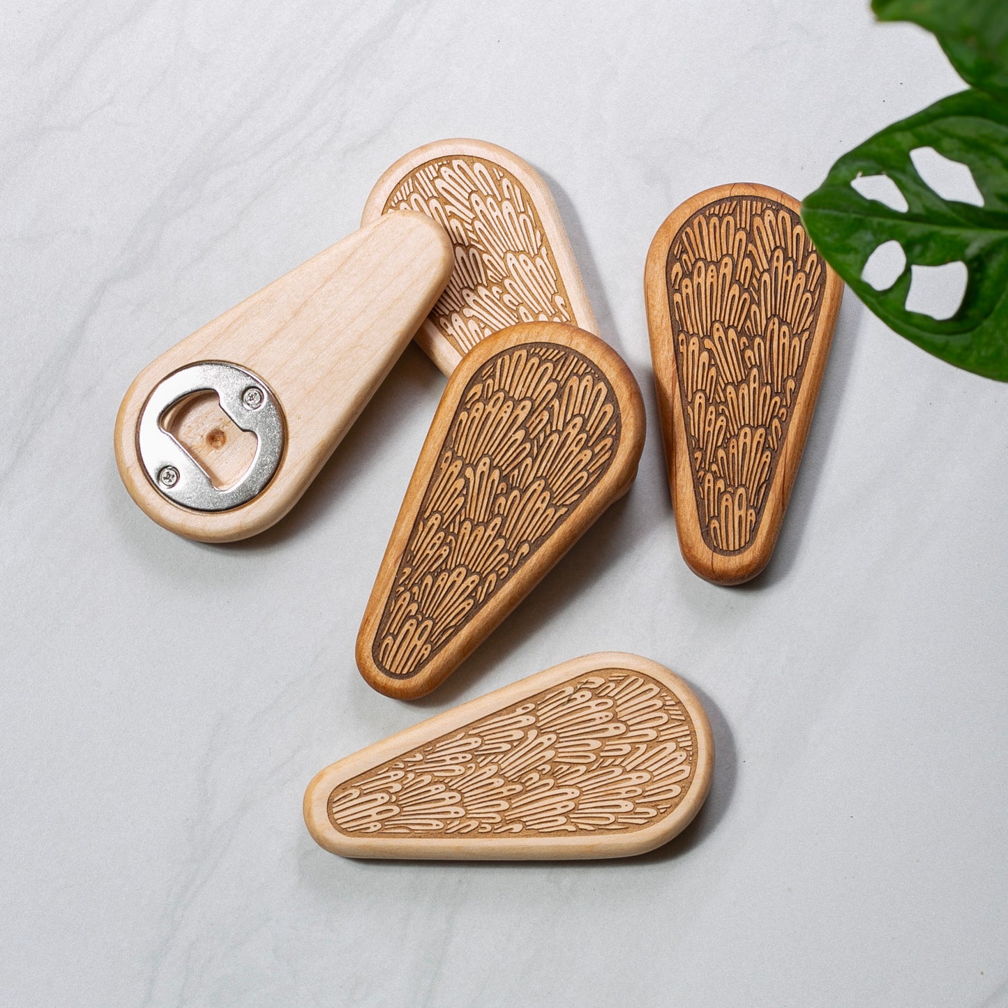 Wooden bottle openers with unique patterns on a light gray surface.