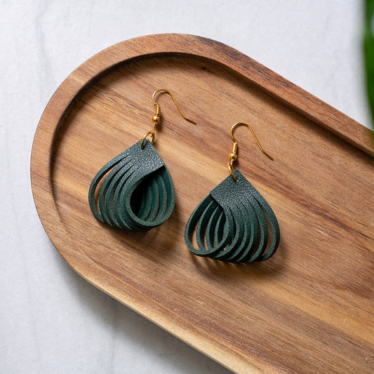 Green leaf-shaped earrings on a wooden tray