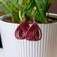 Red earrings hanging in front of a potted plant